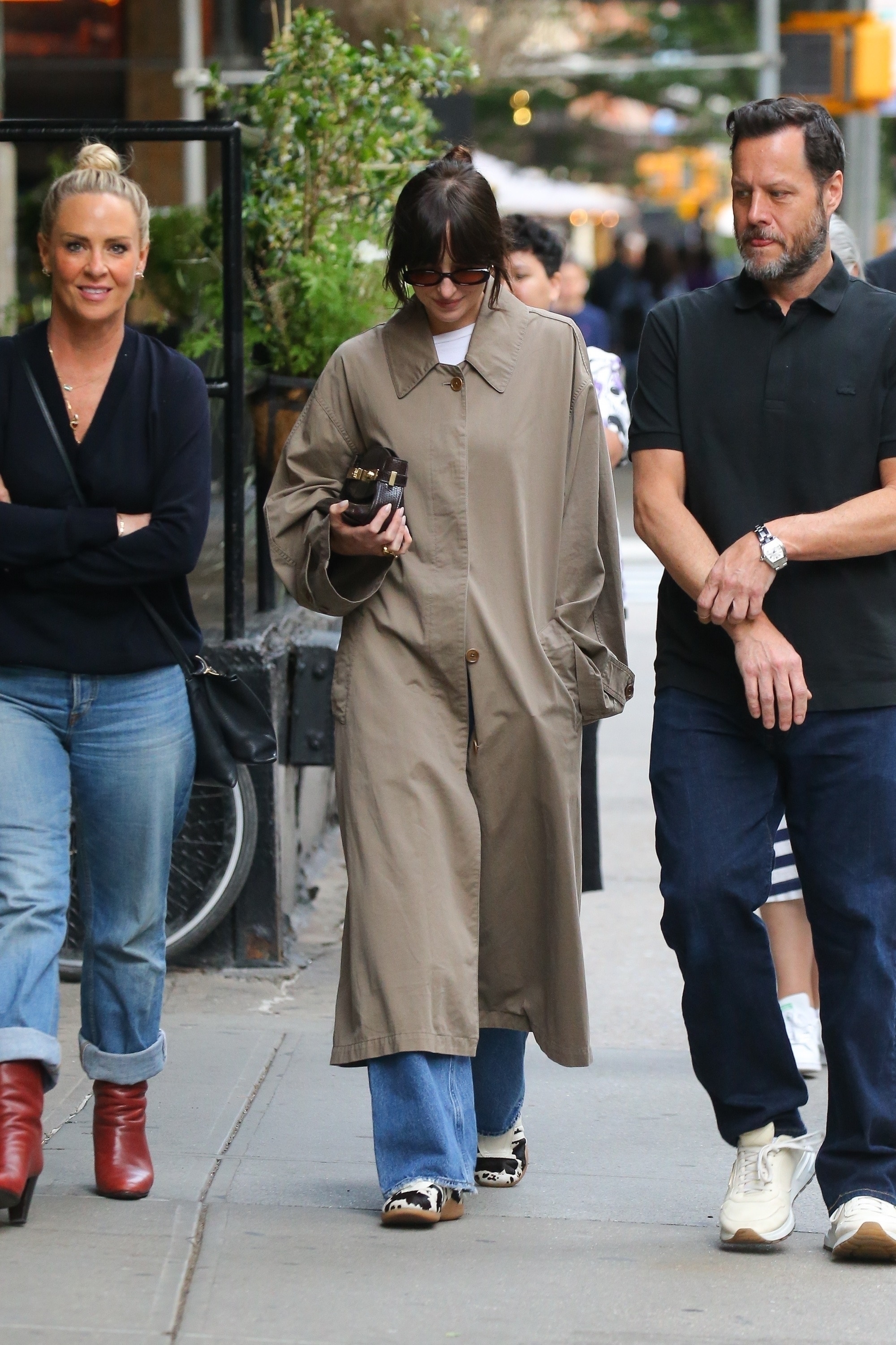 Dakota Johnson wears cow-print sneakers with a long trench coat.