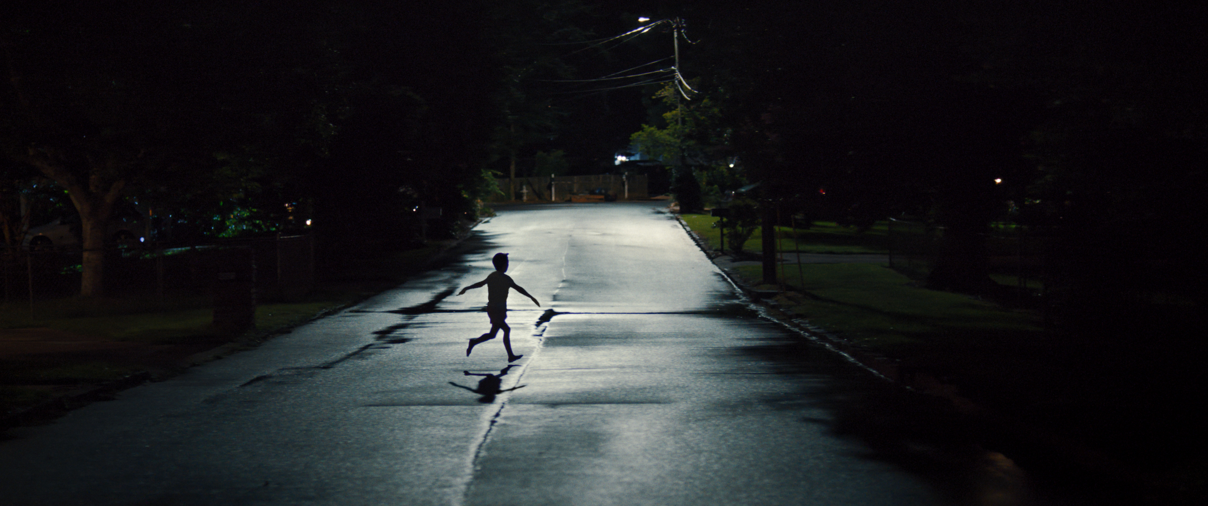 a little boy runs through a dimly lit street in the middle of the night in a still from the movie weapons