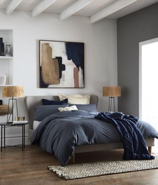 Large scale abstract wall art in modern bedroom scheme, with raffia lamps, and charcoal bedlinen.