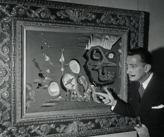 Salvador Dalí points to figures on his "Uranium and Atomica Melancholia Idyll" canvas