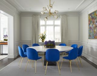 Bold blue dining chairs with gold legs in a neutral dining room