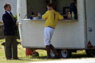 Prince Harry stood at the counter of a burger van in his polo outfit