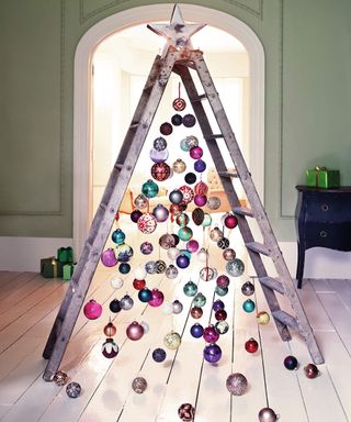 A metal DIY stepladder decorated with assortment of colorful baubles and star tree topper