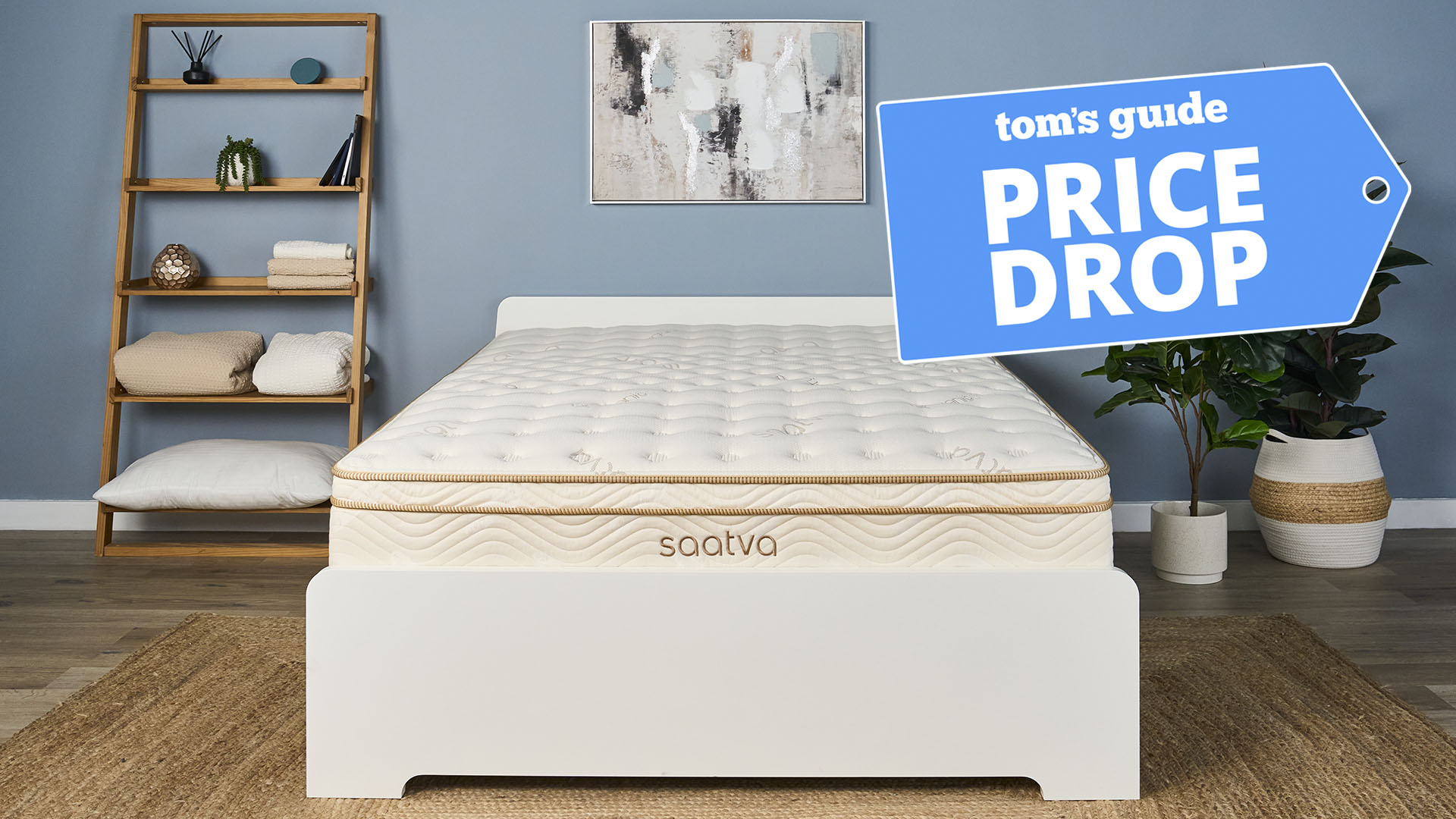 The Saatva Classic, our highest rated mattress, on a bed frame in a bedroom. A Tom's guide price drop deals graphic in the top right corner