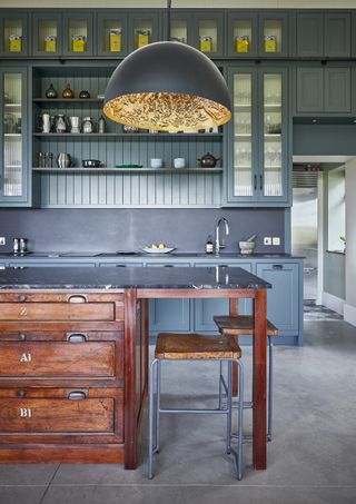 a dark grey kitchen with beadboard and a reclaimed schoolhouse kitchen island