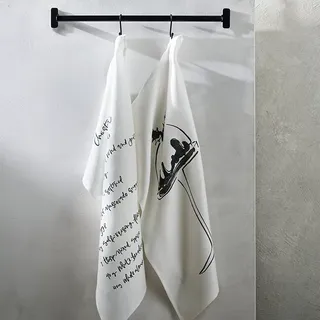 Two white tea towels hanging from a black metal wall mounted rod. Christmas pudding motif printed on 