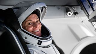nicole mann in a spacesuit smiling inside her spacecraft