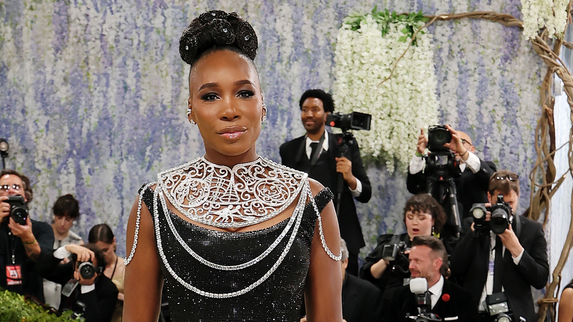 Venus Williams with an updo hairstyle wearing a black off-the-shoulder gown and neck plate at the 2026 Met Gala.