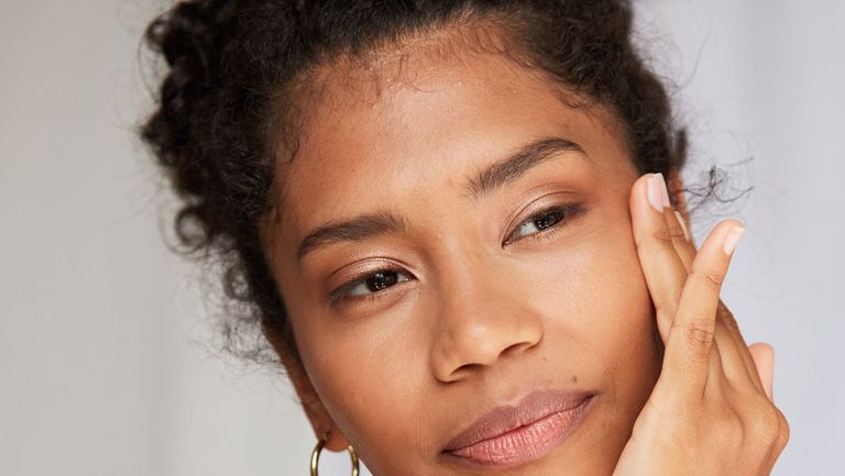 girl touching her face wearing one gold hoop
