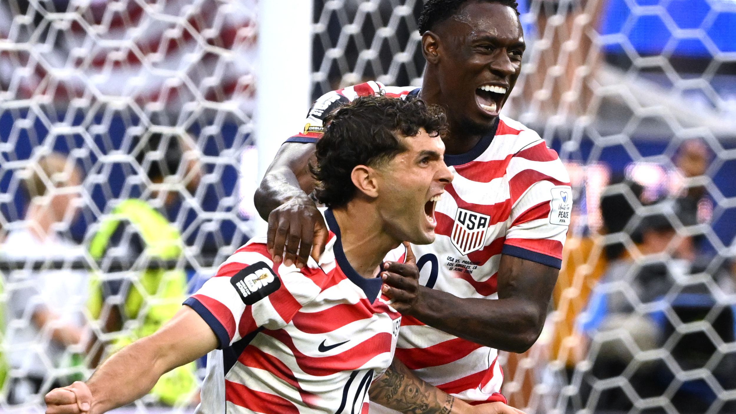 Christian Pulisic and Folarin Balogun celebrate a goal at the World Cup in a 4-1 win for USMNT vs Paraguay