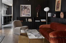 A living room with black walls, a red sofa and a gray chair