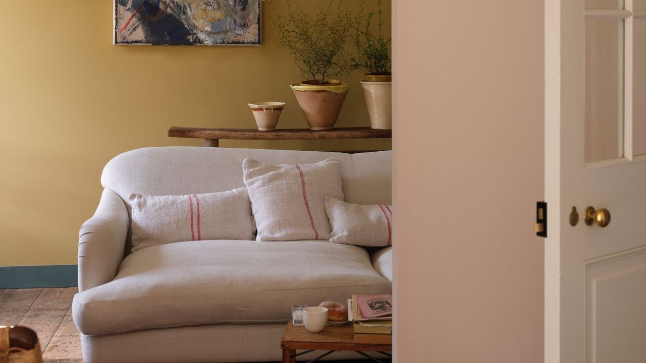 Living room with muted yellow walls, cream sofa and wooden floors