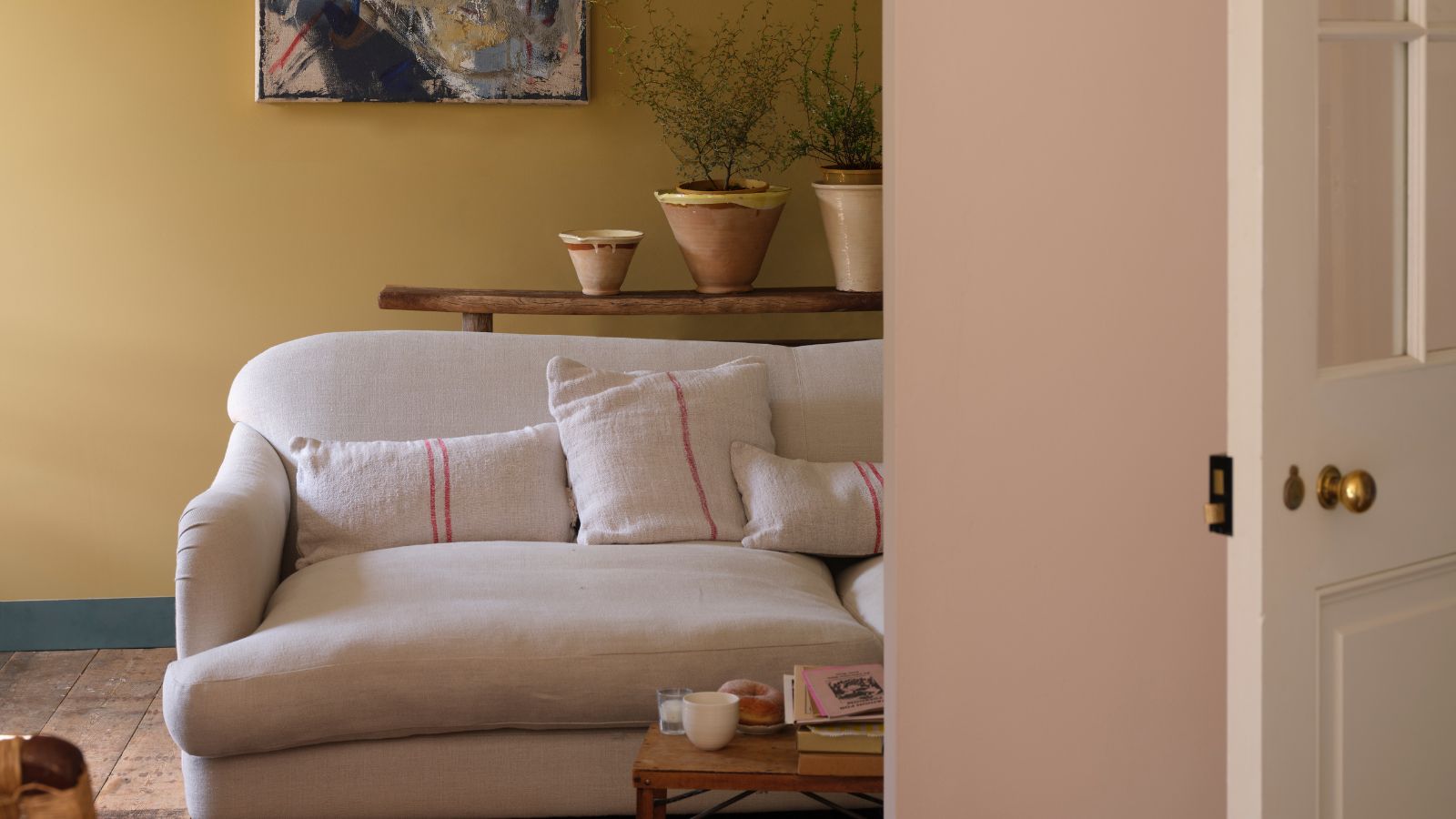 Living room with muted yellow walls, cream sofa and wooden floors