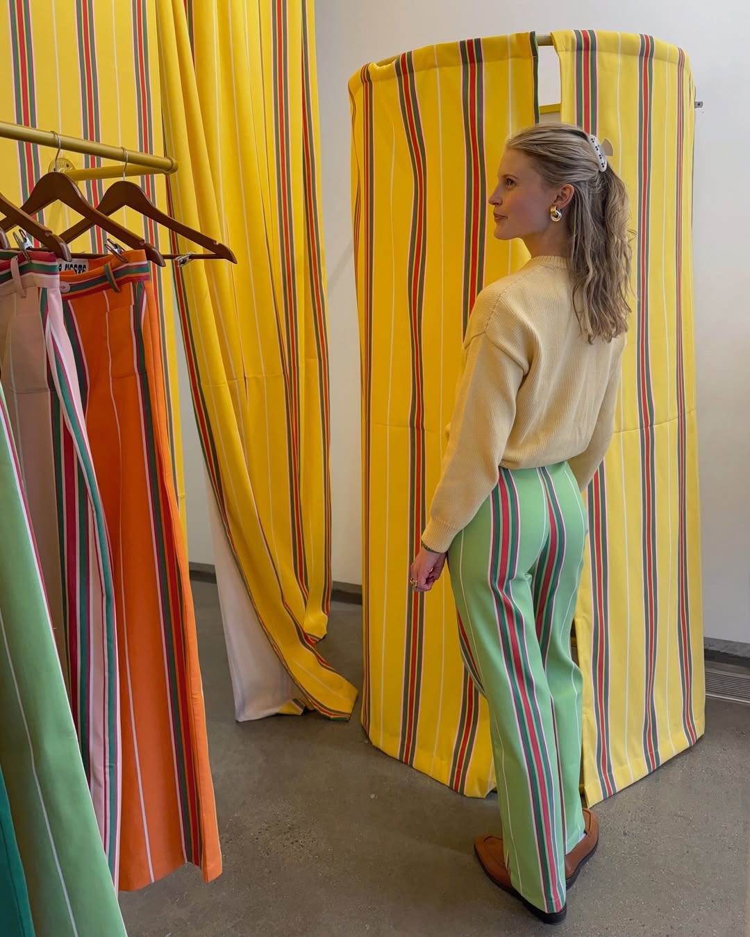 Influencer Lauren wears green and red striped cotton pants from La Veste with a butter yellow cardigan.