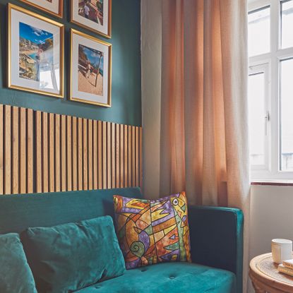 Living room with green sofa and wall panelled portion.