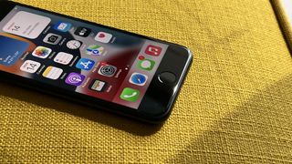 En iPhone SE 2022 ligger på en gul textilyta med skärmen vänd uppåt.