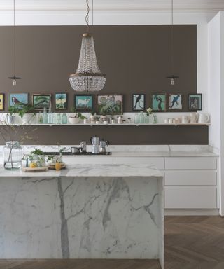 Artwork, wooden floor, white cabinets, marble island, mushroom colored walls, open shelving,