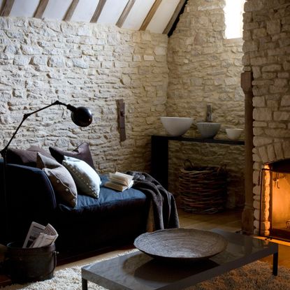 Living room with exposed brick walls, blue sofa, floor reading lamp and fireplace