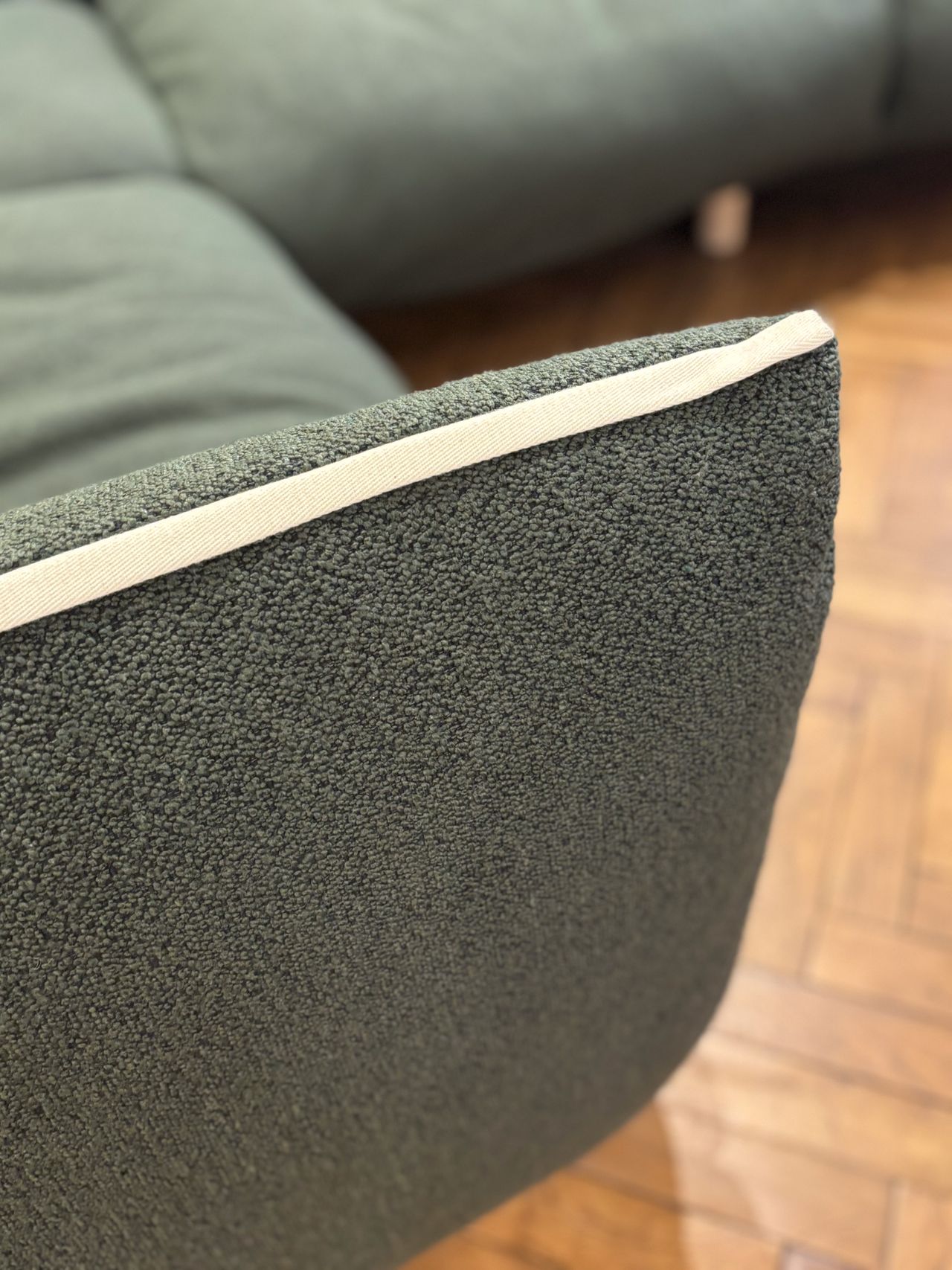 a green cozmo pillow sofa in a showroom with parquet floors and panelled wall