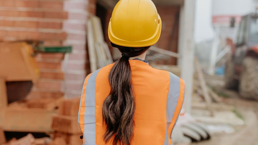 woman wearing a hard hat and high vis jacket looking at building site