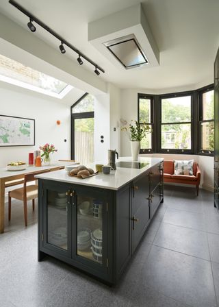 A large black kitchen island with a white countertop to add sharp contrast. One side of the island has glass door cabinets with bowls and plates inside.