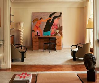 Art Deco style living room with abstract art, wood desk, curved armchairs, antique bust and wood floor