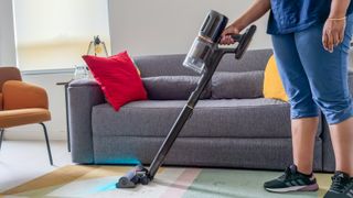 A person using the Dreame Z50 Station on a carpet in front of a couch