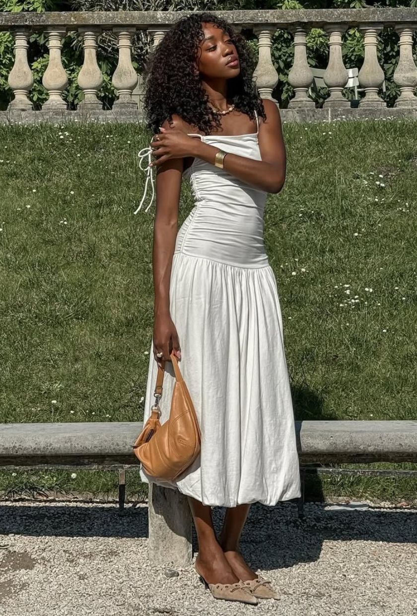 @emmanuellek_ trägt ein weißes Midikleid mit Ballonsaum, hellbraune Pantoletten und eine hellbraune Wildledertasche