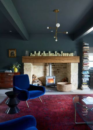 Dark blue living room with velvet blue chairs and red rug