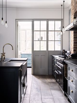 Shaker style black and white kitchen ideas with hints of rustic beauty such as the traditional stove and oven and brass fixtures