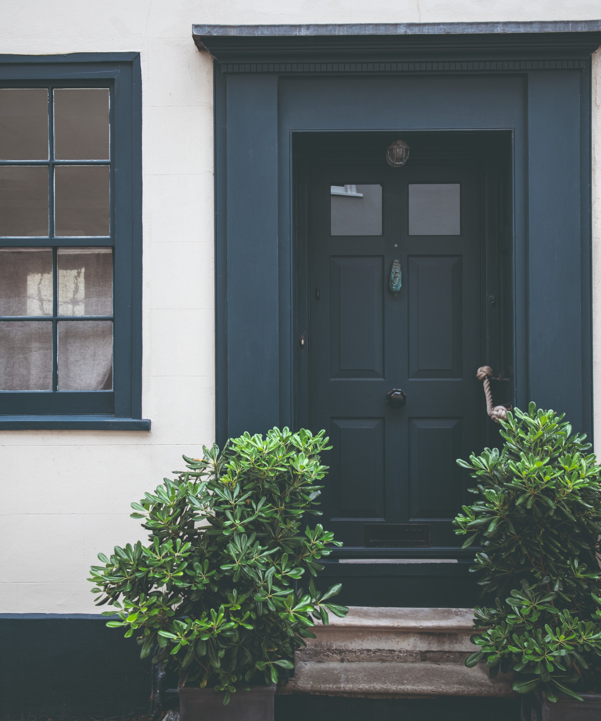 A dark blue-painted front door with a tonal porch and matching window frames