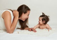 A mom smiles at her baby, with their faces close together