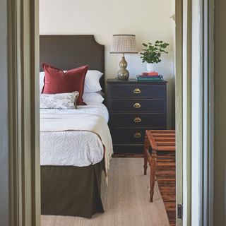 bedroom with deep sage green bed and painted chest of drawers side table