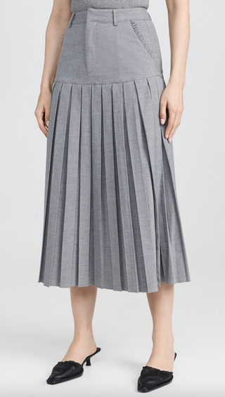 a woman wearing a below the knee midi pleated skirt