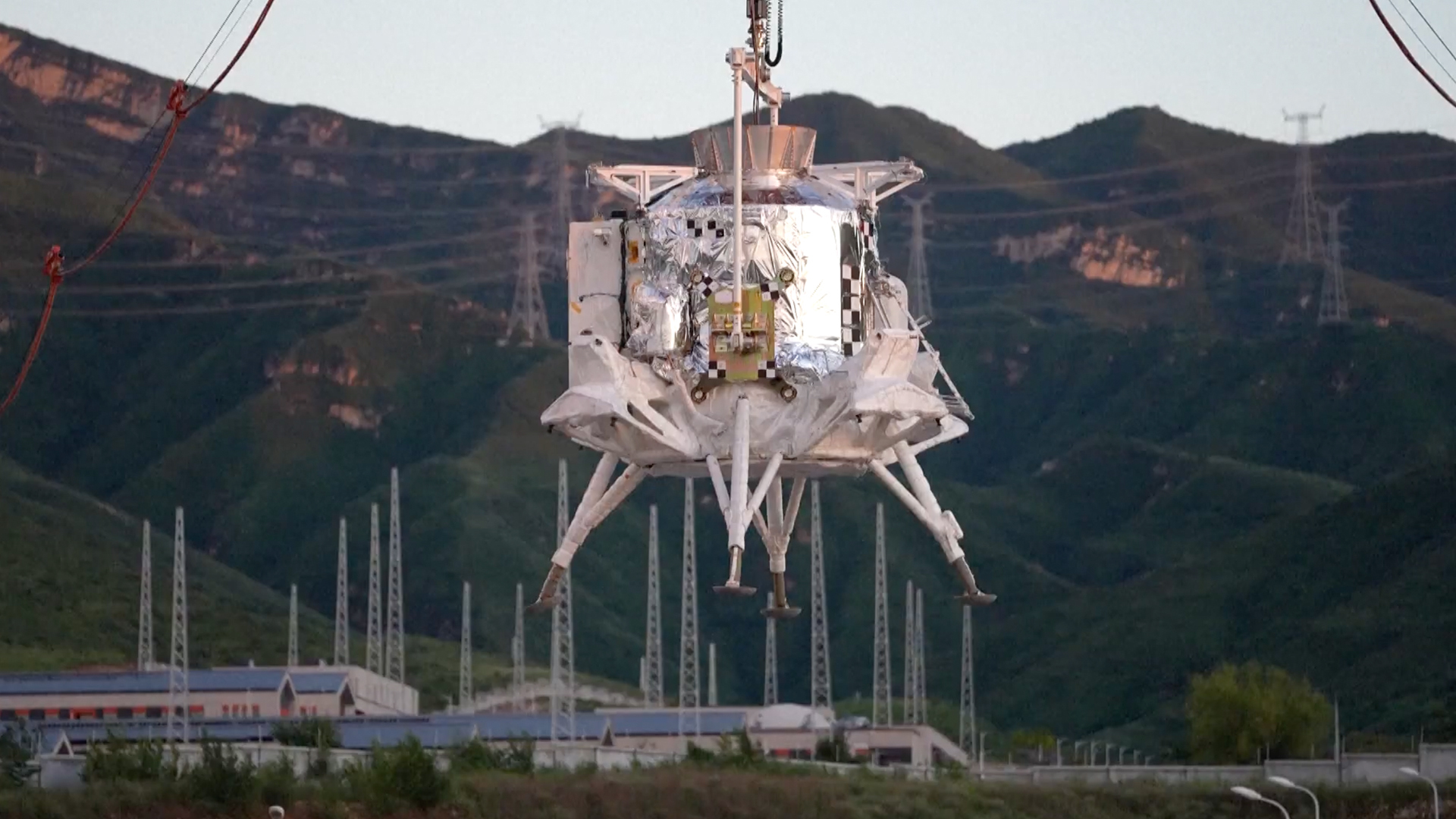 China's lunar lander, with four legs, floats down to the surface of Earth via parachute