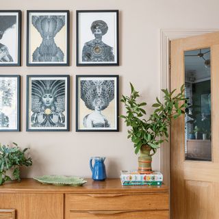 Picture wall of six black and white prints with teak furniture