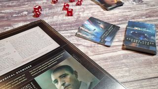The adventure book, cards, and dice from the Blade Runner RPG on a wooden surface