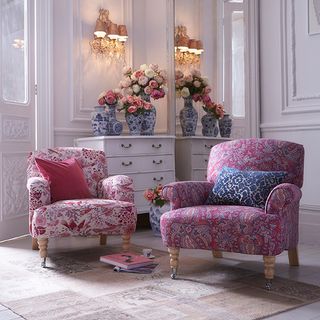 white living room with pink armchairs and flower vases