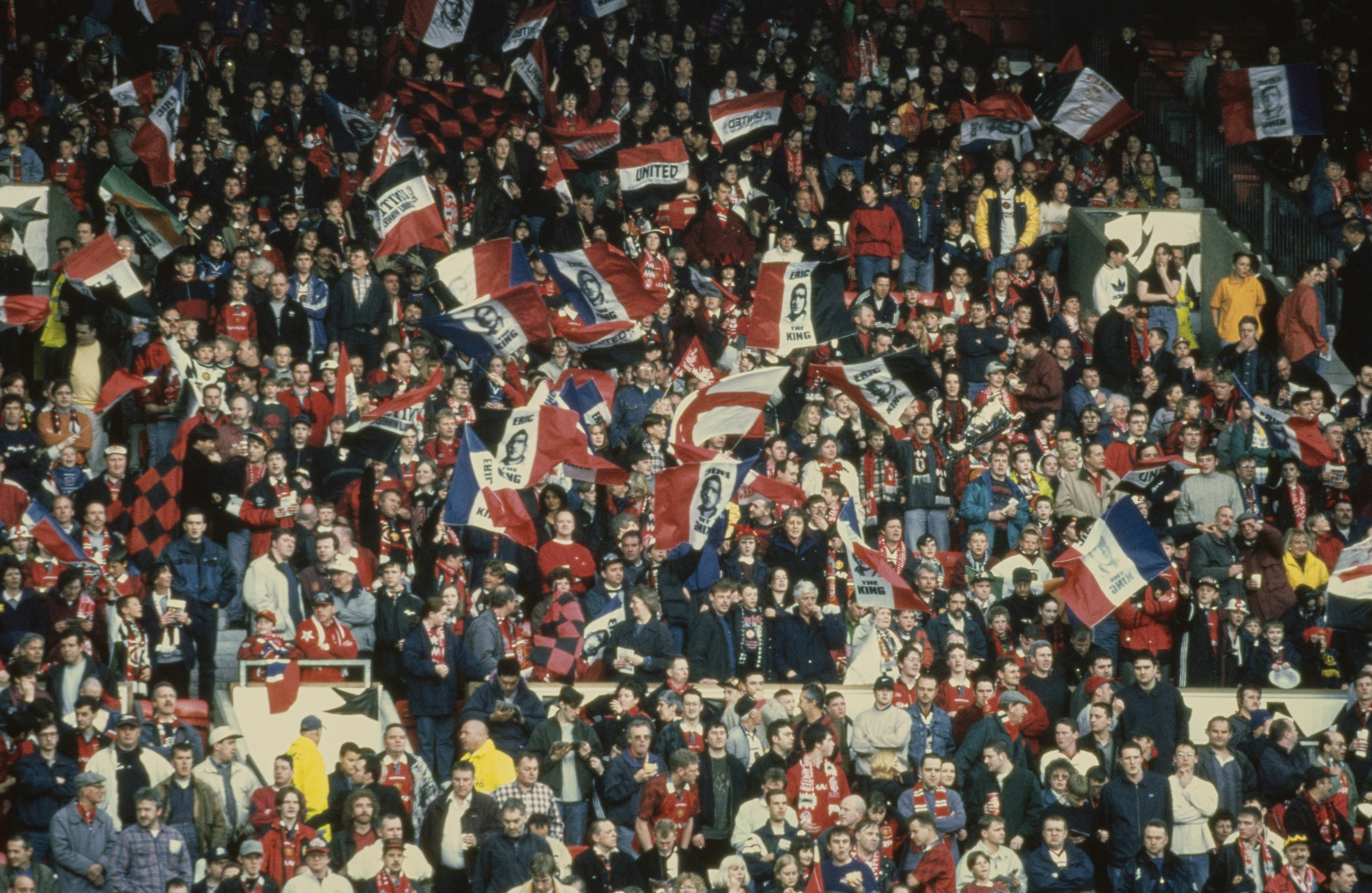 Manchester United fans wave flags with the words 