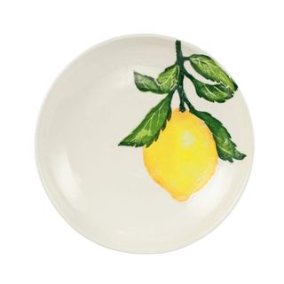 A round stoneware plate with a painted lemon with green leaves on it