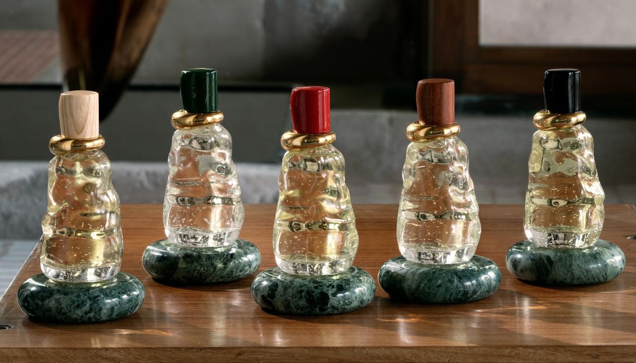 five glass bottega veneta perfume bottles on green marble pedestals 