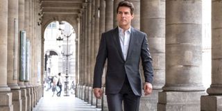 Tom Cruise dressed in a suit, walking during the day in Mission: Impossible - Fallout.