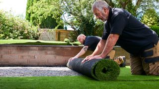 Two workers Installing artificial grass in modern garden of home