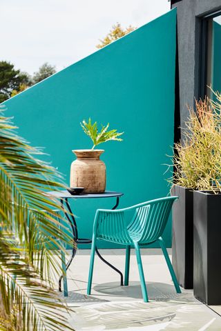 apartment patio with turquoise wall, bistro seating, planters