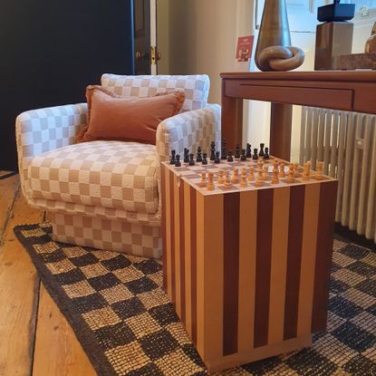 The Dunelm Harmon games side table set for a game of chess on top of a chequerboard rug and next to a chequerboard-print armchair at the brand's spring/summer 2026 press showcase