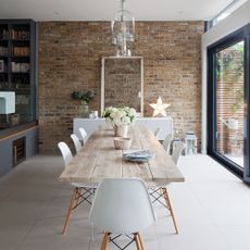 dining room with brick walls and wooden table with white chairs