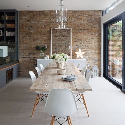 dining room with brick walls and wooden table with white chairs