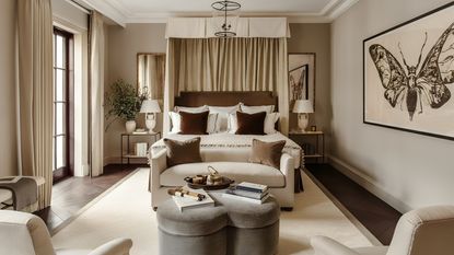 A master bedroom suite with a large bed footed by a cream sofa.