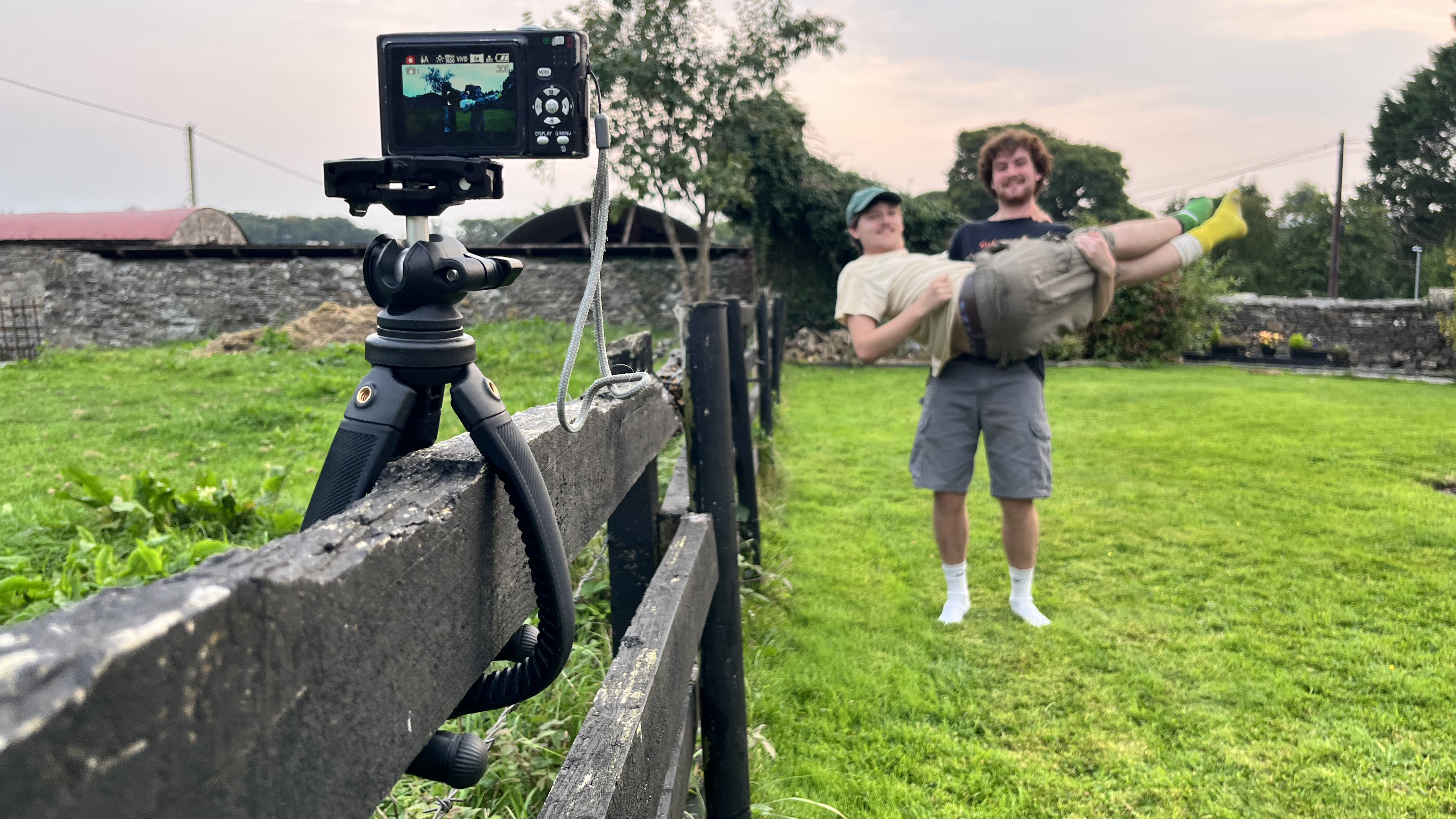 Freewell Vlogpod on a fence with compact camera and two men posing 