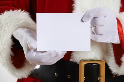 Santa Claus holding a blank piece of paper.